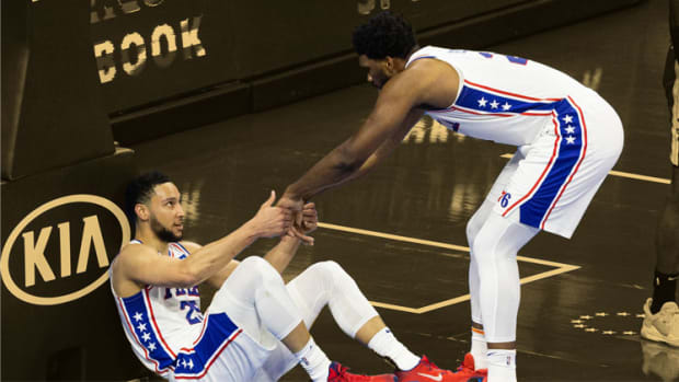Philadelphia 76ers guard Ben Simmons is helped up by center Joel Embiid