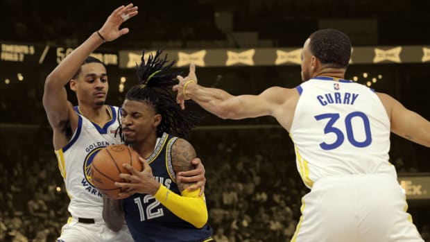 Memphis Grizzlies guard Ja Morant drives to the basket as Golden State Warriors guards Jordan Poole and Stephen Curry defend
